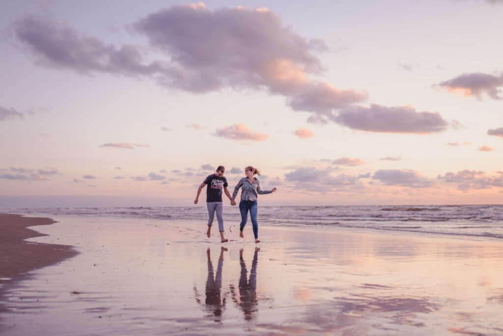 Intiem moment tussen een stel tijdens een fotoshoot aan het strand met de golven op de achtergrond