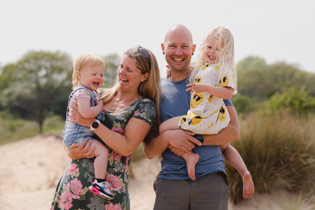 Knus moment tussen ouders en kinderen tijdens een gezinsshoot in de duinen