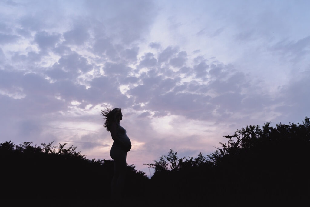 Stralende zwangere vrouw in een jurk tijdens een fotoshoot in de natuur